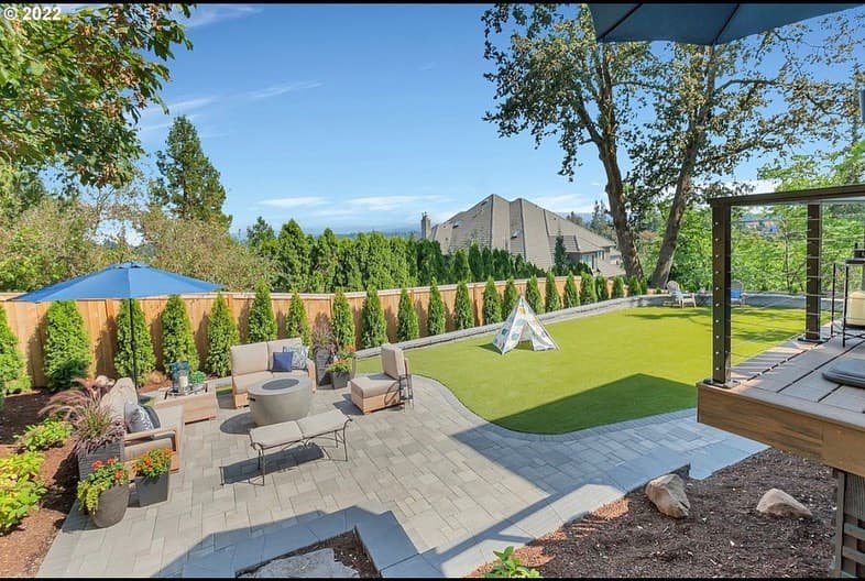 Aerial view of finished GI hardscape — paver patio, turf, deck, mountain horizon