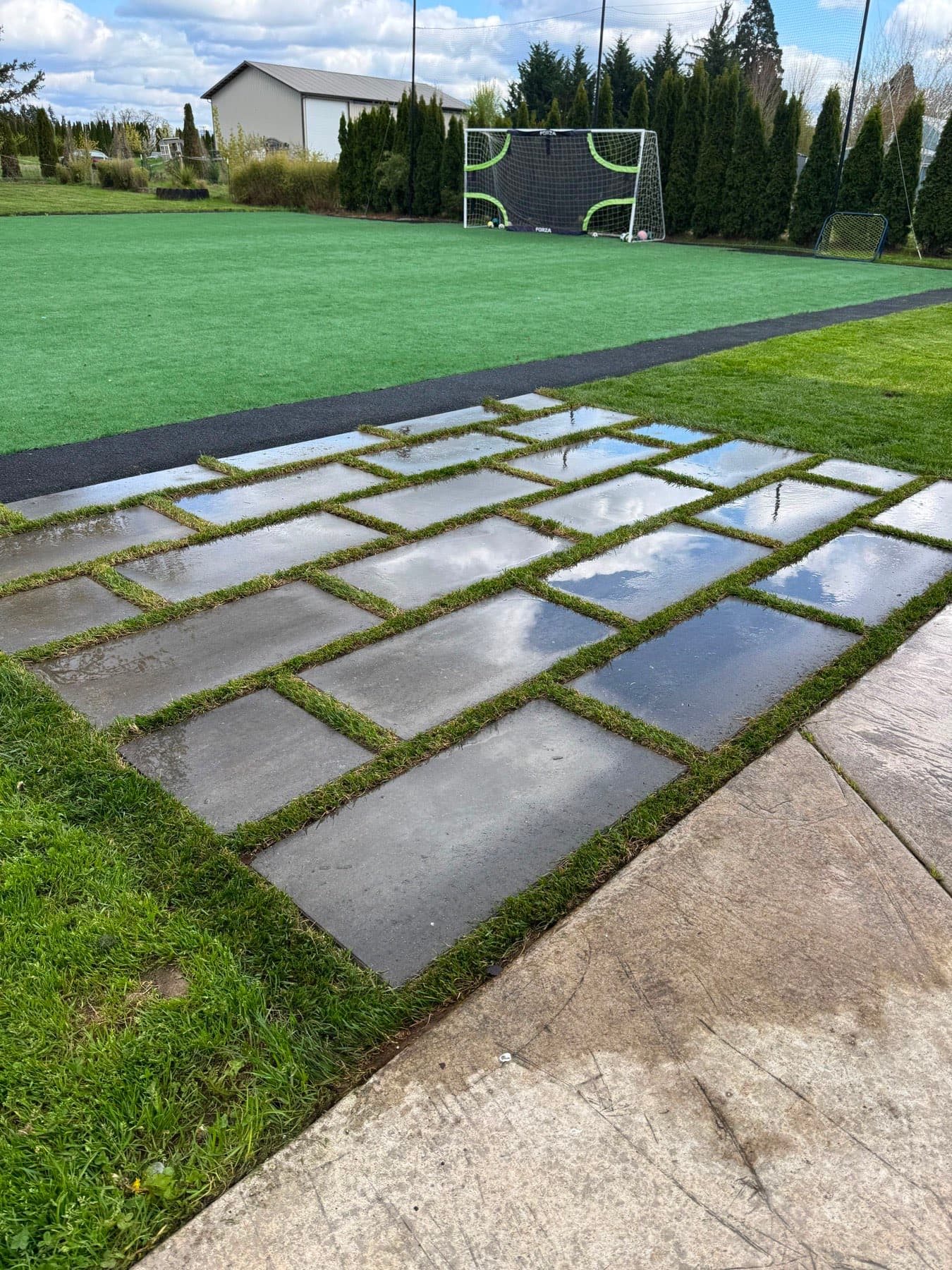 Large artificial turf sports lawn with soccer goals, approached by turf-jointed paver squares, installed by GI Landscape