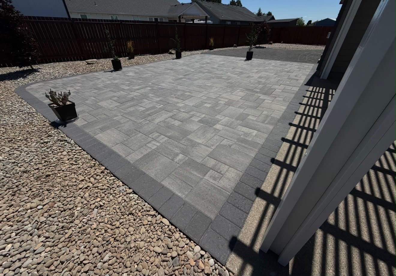 Grey paver patio with a charcoal soldier border set into a gravel surround in a new-build backyard, by GI Landscape