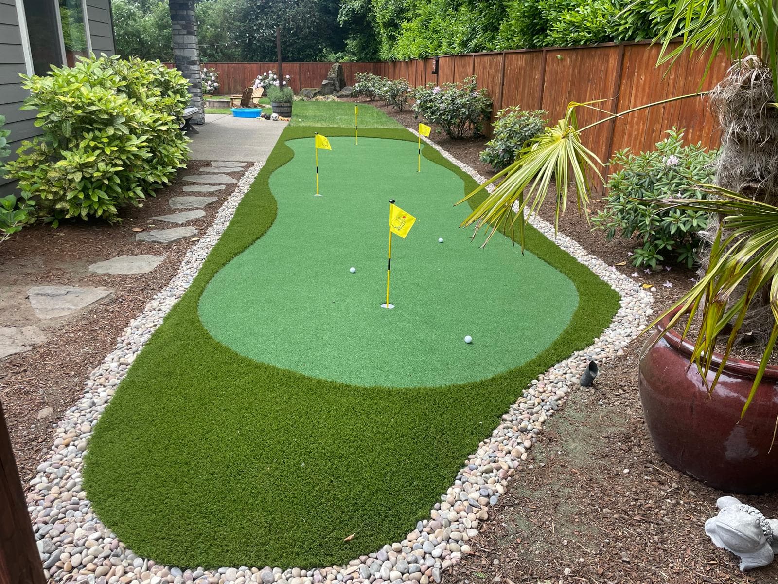 Backyard putting green built from artificial turf with cup and flag, by GI Landscape