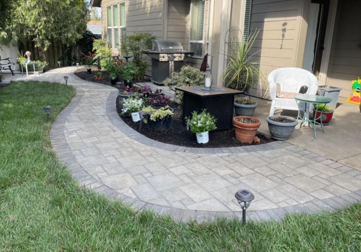 Paver patio with a pergola and lounge seating in a fenced backyard by GI Landscape