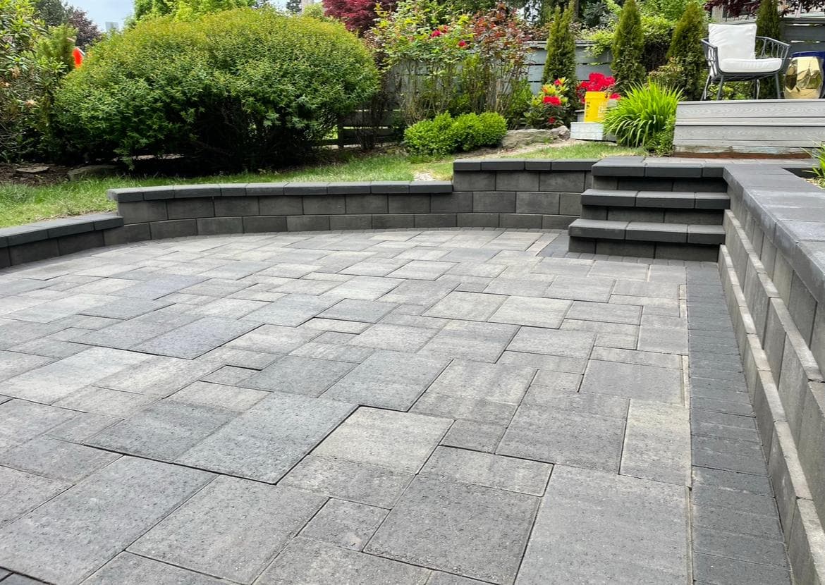 Tiered paver patio with built-in steps on a sloped lot, by GI Landscape