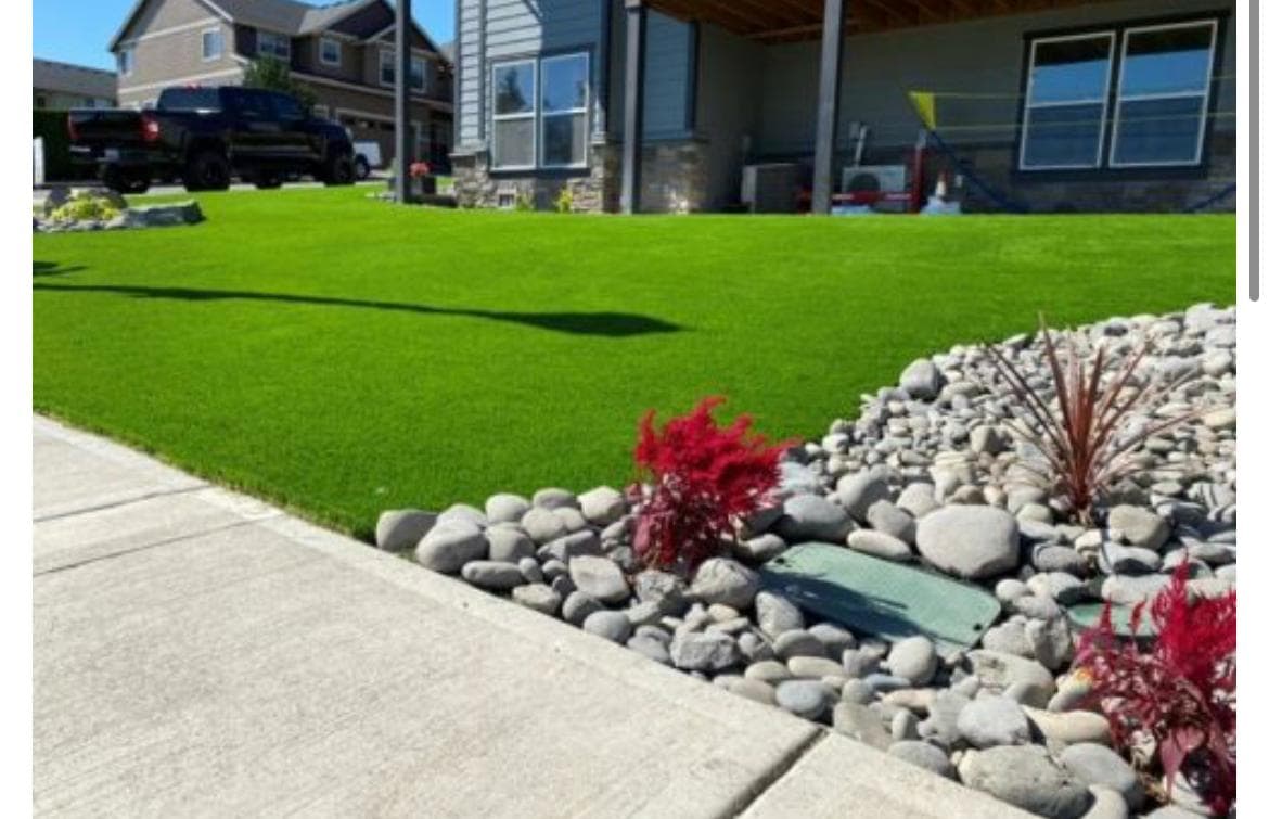 Artificial-turf lawn edged with a river-rock border and plantings, by GI Landscape