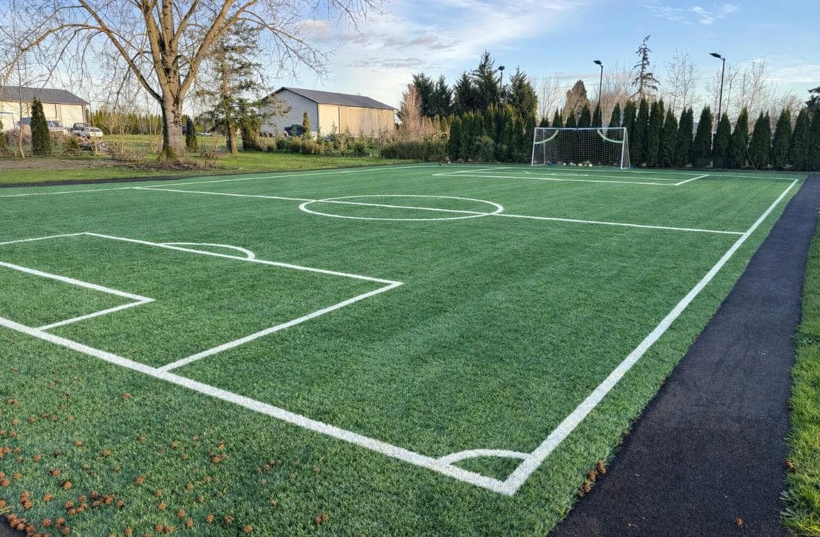 Full-size artificial-turf soccer pitch with painted lines and a goal, by GI Landscape