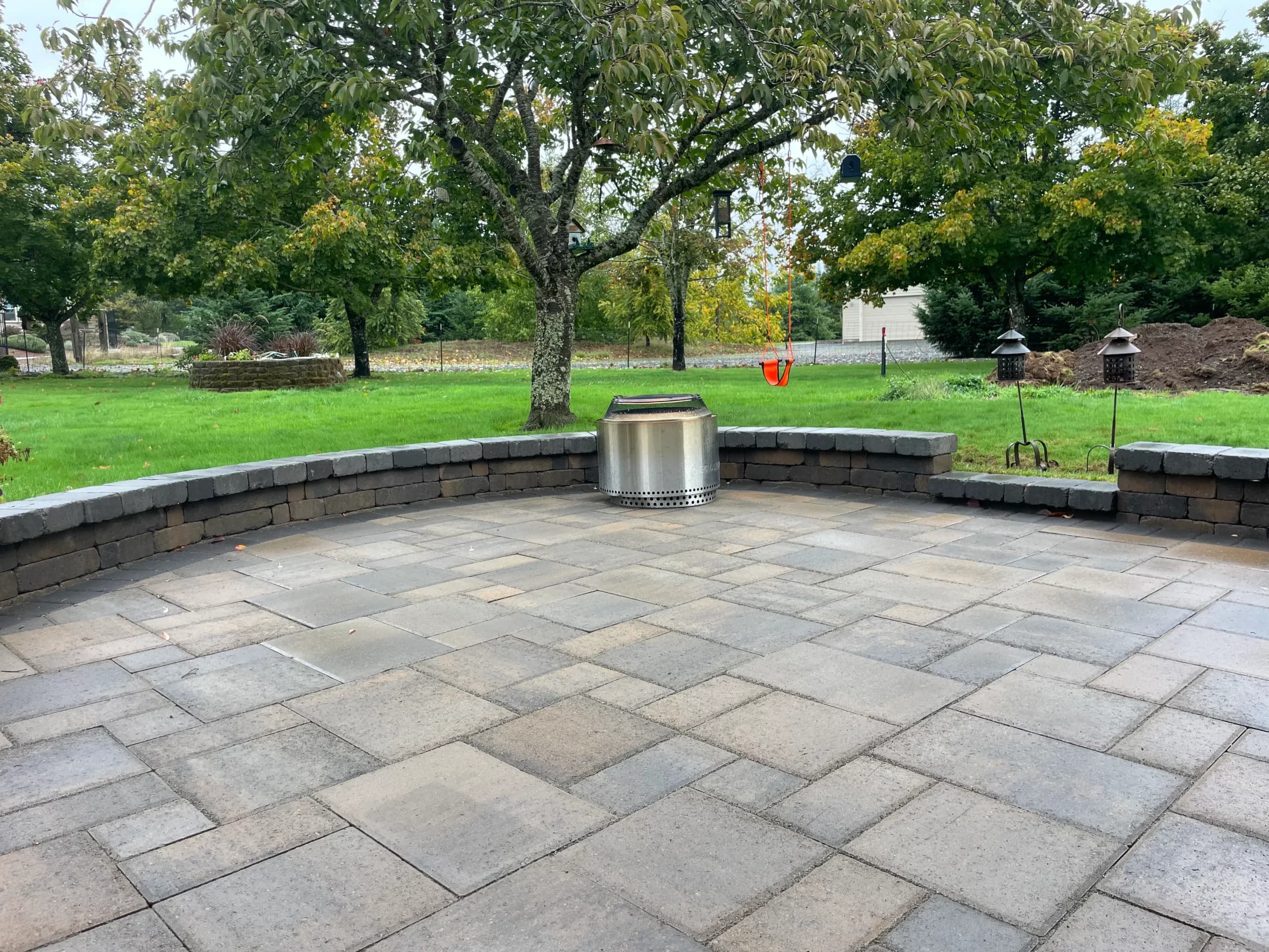 Circular paver patio with curved seat wall and stainless gas fire pit